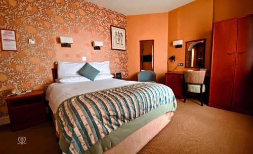 a hotel room with a bed and a chair at Metropole Hotel and Spa in Llandrindod Wells