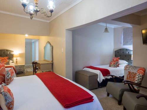 a bedroom with two beds and a red blanket at Fouriesburg Country Inn in Fouriesburg