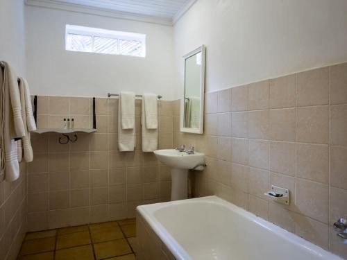 a white bathroom with a sink and a tub and a sink at Fouriesburg Country Inn in Fouriesburg