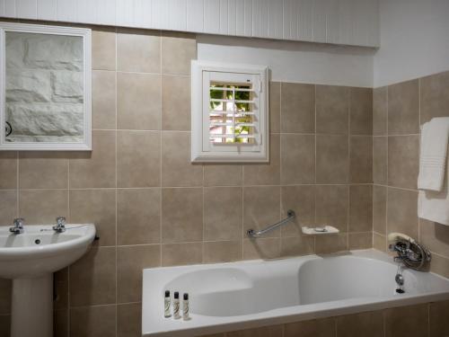 a bathroom with a bath tub and a sink at Fouriesburg Country Inn in Fouriesburg