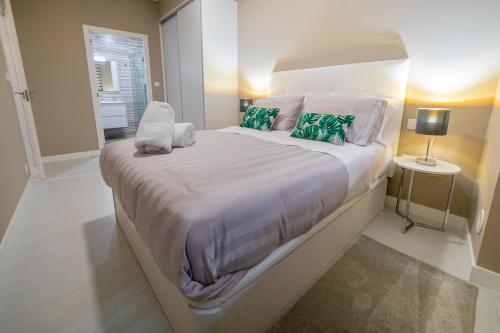 Un dormitorio con una gran cama blanca con almohadas verdes. en LOFT CABANELAS, en Cangas de Morrazo