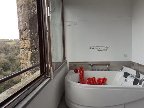 a bathroom with a tub and a toilet and a window at La casa nel Borgo Sospeso "con vasca e vista panoramica" in Vitorchiano