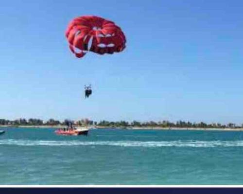 a red parachute flying over the water with a boat at sea view apartment in Porto Marina hotel tower in El Alamein