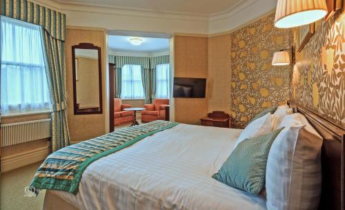 a hotel room with a large bed and a mirror at Metropole Hotel and Spa in Llandrindod Wells