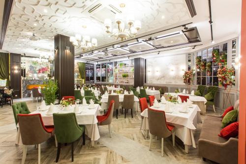 un restaurante con mesas blancas y sillas verdes en Eco-hotel Lel', en Ufa