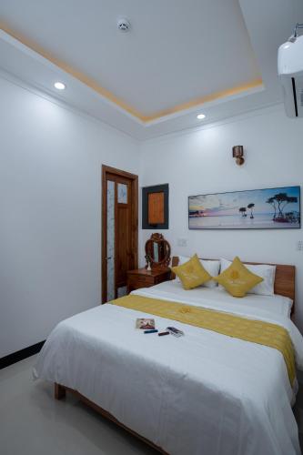 a bedroom with a large white bed with yellow pillows at Kim Hoàn Hotel Phan Rang in Phan Rang