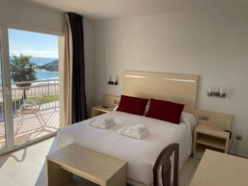 a bedroom with a bed with red pillows and a balcony at Hotel Reimar in Sant Antoni de Calonge