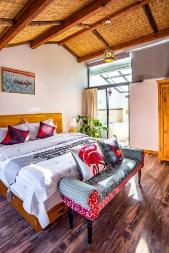 a bedroom with a large bed and a bench at Baisha Flamingo Hotel in Lijiang