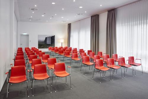 a conference room with red chairs and tables at LÉGÈRE HOTEL Luxembourg in Luxembourg