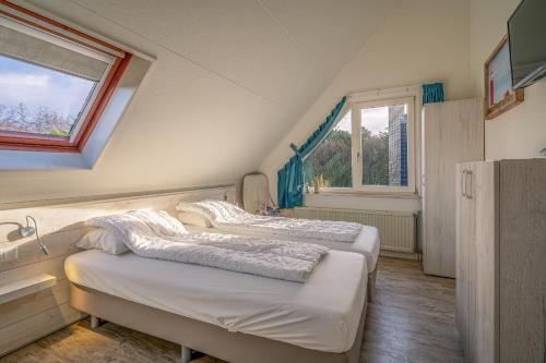 Dos camas en una habitación con ventana. en Villapark Kamperfoelie 81, en De Koog