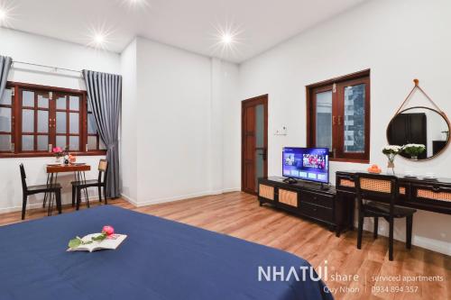 a living room with a table and a tv at NHATUIshare Quy Nhơn in Quy Nhon