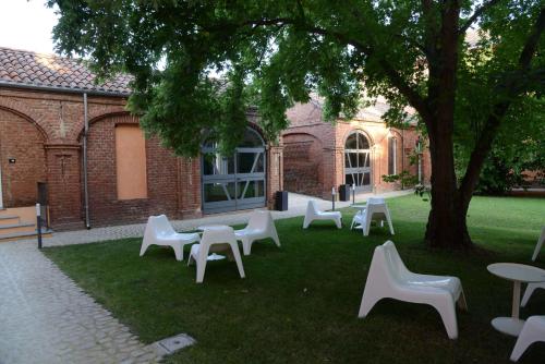 a group of white chairs and tables under a tree at Tenuta La Fiscala in Alessandria