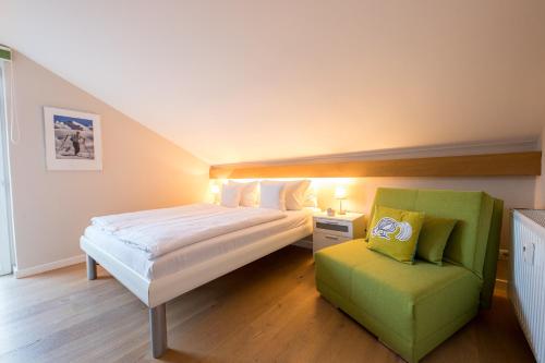 a bedroom with a bed and a green chair at Überflieger in Garmisch-Partenkirchen