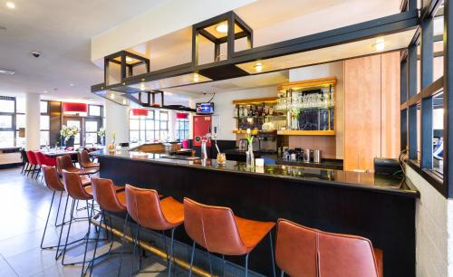 a bar with orange chairs at a restaurant at Bastion Hotel Amsterdam Zuidwest in Amsterdam