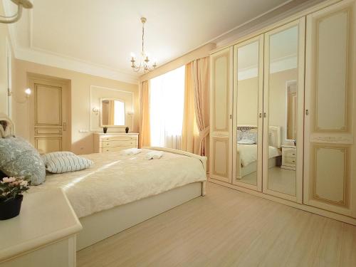 biała sypialnia z dużym łóżkiem i lustrem w obiekcie Евро у Пушкинки w mieście Omsk