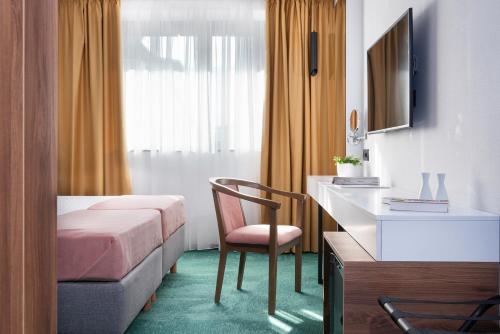 a bedroom with a bed and a desk and a chair at Hotel Tim's in Skopje