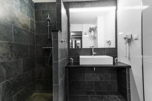 a black and white bathroom with a sink and a mirror at Bastion Hotel Almere in Almere