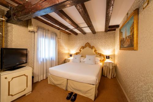 a bedroom with a white bed and a television at Hotel Antico Doge - a Member of Elizabeth Hotel Group in Venice