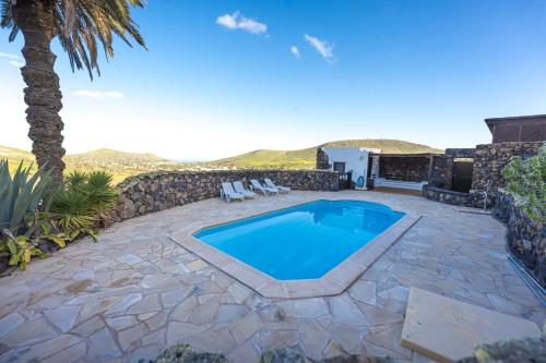 a patio with a swimming pool and a palm tree at Finca La Fuentecilla in Haría