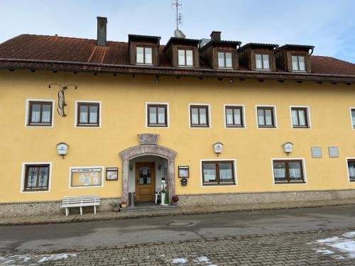 a yellow building with a bench in front of it at Gasthof zum Kirchenwirt in Kirchdorf am Inn