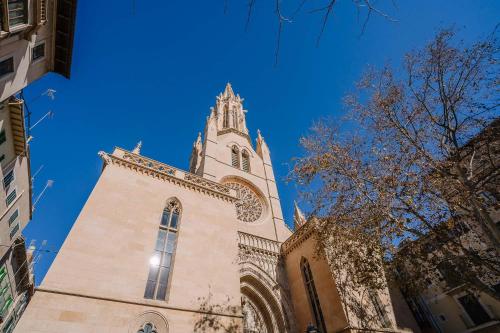 a church with a tower with a blue sky in the background at Vintage Palma Palace Apartments TI in Palma de Mallorca