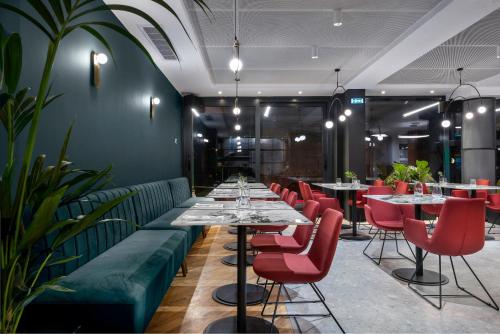a restaurant with long tables and red chairs at Hotel Tim's in Skopje