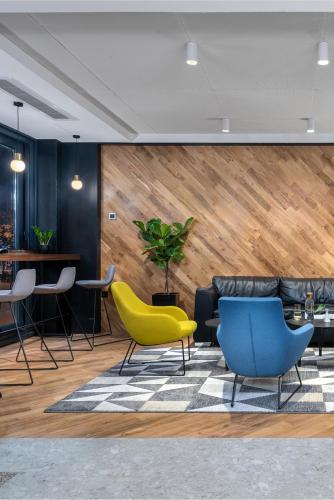 a lobby with yellow and blue chairs and a table at Hotel Tim's in Skopje
