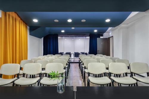 a conference room with white chairs and a table at Hotel Tim's in Skopje