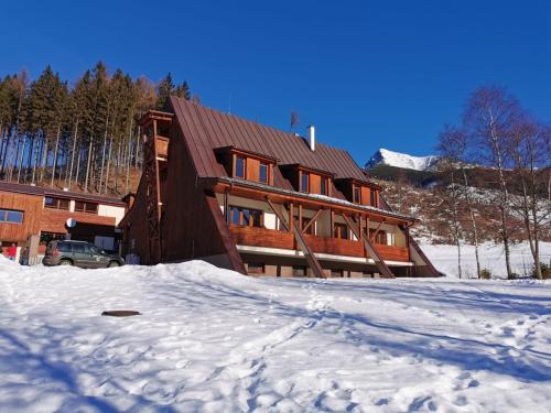 une grande maison en bois dans la neige dans l'établissement Tri studničky, à Štrbské Pleso