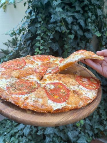 a person holding a slice of pepperoni pizza on a plate at Karavella in Mykolaiv