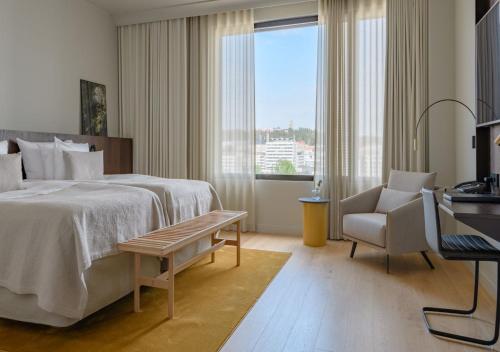 a bedroom with a bed and a chair and a window at Solo Sokos Hotel Paviljonki in Jyväskylä