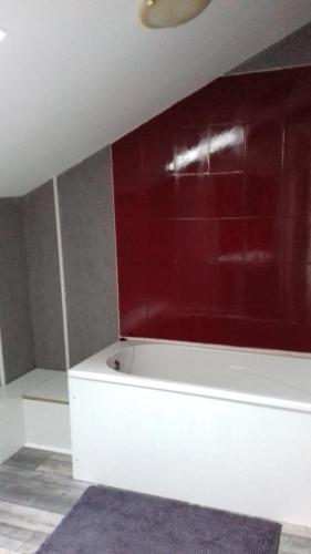bañera blanca en una habitación con pared roja en Gîte de la Py en Dontrien