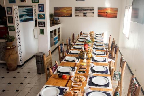 une grande salle à manger avec une grande table et des assiettes de nourriture dans l'établissement Ifni Surf Hostal, à Sidi Ifni