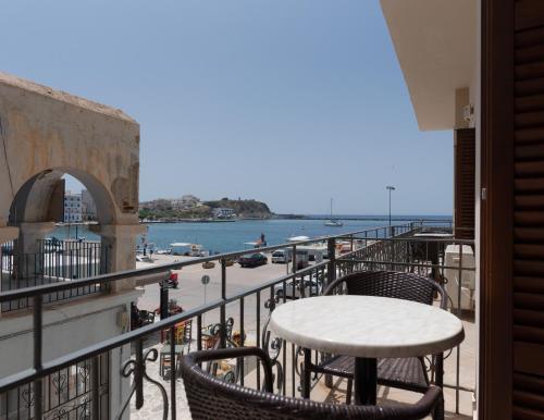 a table and chairs on a balcony overlooking the water at Poseidonio Hotel in Tinos Town