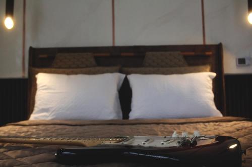 a guitar on a bed with white pillows at Ecco Superior in Novi Pazar