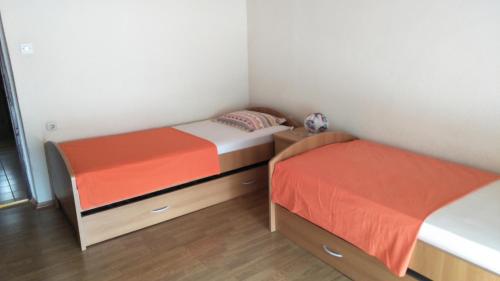 two beds in a small room with wooden floors at Apartments Jere in Primošten