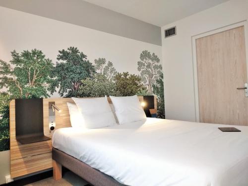 a bedroom with a large white bed and a wall with trees at Novotel Suites Montpellier Antigone in Montpellier