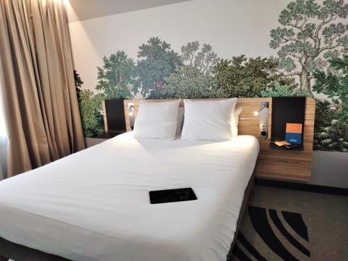 a bedroom with a large bed with white sheets and pillows at Novotel Suites Montpellier Antigone in Montpellier