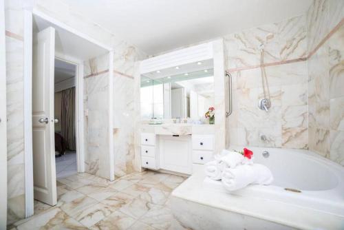 a white bathroom with a tub and a sink at Appartement 1 chambre Sapphire Beach in Cupecoy