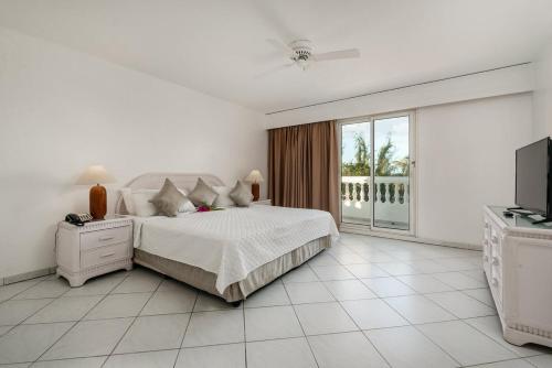 a white bedroom with a bed and a television at Appartement 1 chambre Sapphire Beach in Cupecoy