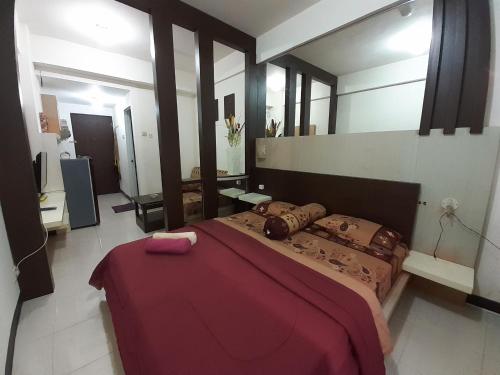 1 dormitorio con 1 cama grande y espejo grande en Apartemen SUKARNO HATTA Elwarda Ely, en Malang
