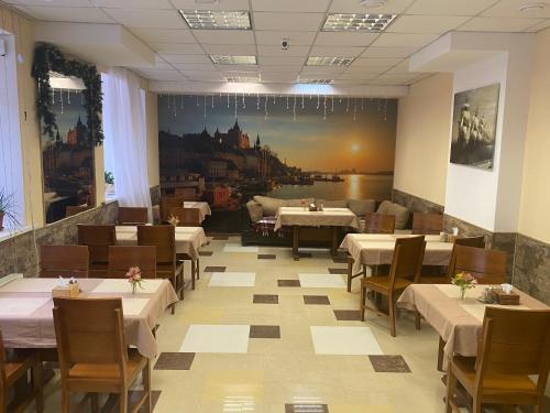 ein Restaurant mit Tischen und Stühlen und einem Gemälde an der Wand in der Unterkunft Karavella in Mykolajiw