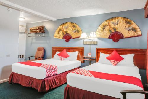 2 camas en una habitación de hotel con almohadas rojas en OYO Hotel Liberal, Kansas en Liberal