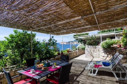 una mesa y sillas en un patio con vistas al océano en Apartment Helena, en Dubrovnik