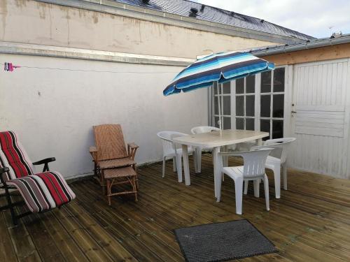 een patio met een tafel en stoelen en een parasol bij Studio Calme in Ouistreham