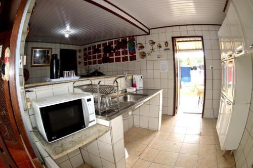 a kitchen with a sink and a microwave at Pousada da Geisa in Bertioga