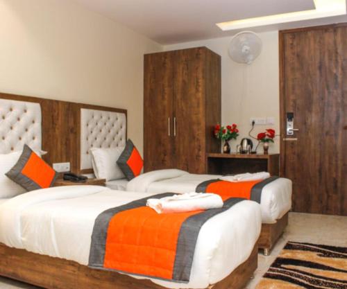 a bedroom with two beds with orange and black blankets at Mayda Inn- A Boutique Hotel in New Delhi