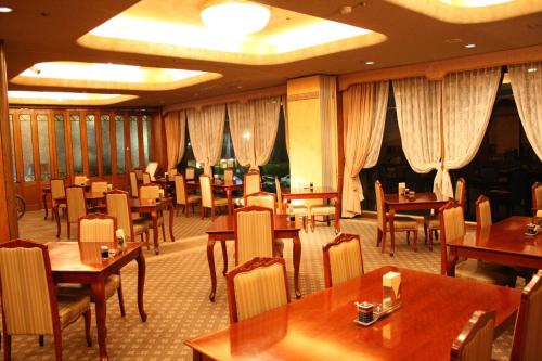 a restaurant with wooden tables and chairs and curtains at Sunsky Hotel in Kitakyushu