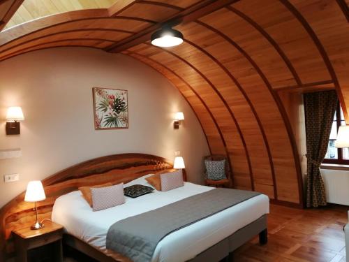 a bedroom with a large bed with a wooden ceiling at Hotel La Diligence in La Ferté-Saint-Cyr