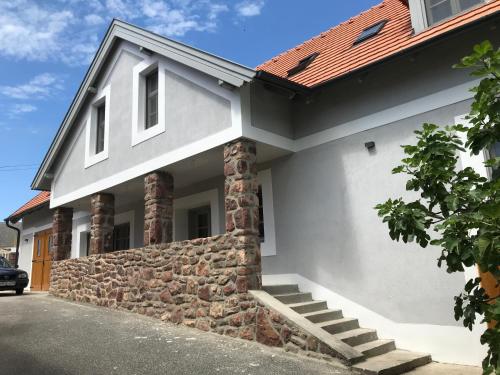 a white house with a stone wall at Fügekert - Bed&Wine in Zánka